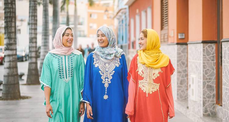 Drei Frauen in traditioneller Kleidung gehen auf einer Straße.