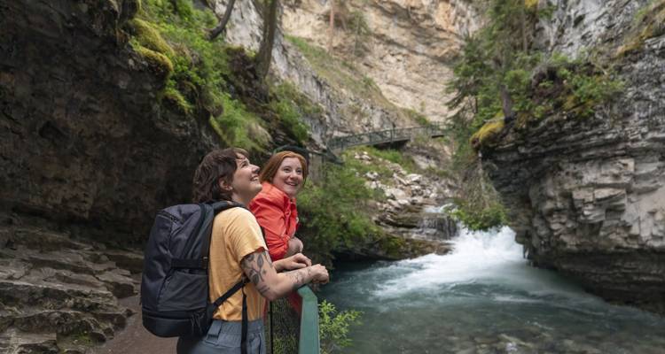 People enjoying a valley with a stream and rocky cliffs.