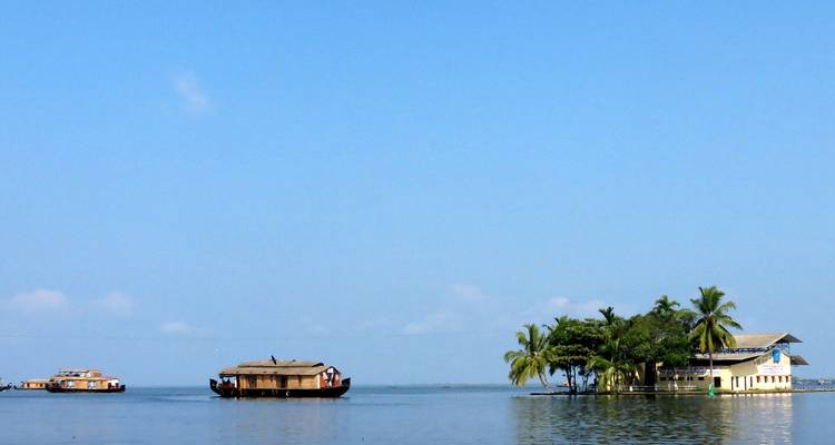 Open meer met woonboten en een klein eiland met palmbomen.