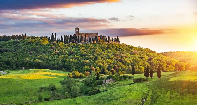 Scenic hills and a church in Tuscany at sunset.