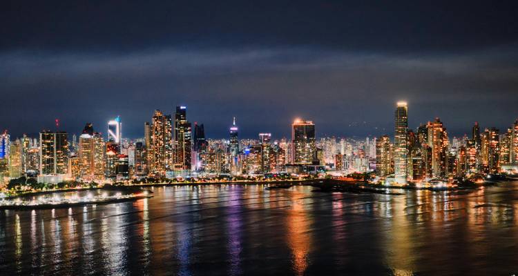 Panorama de la ligne d'horizon d'une ville illuminée la nuit au bord de l'eau.