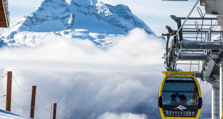 Une télécabine avec les montagnes enneigées en arrière-plan.