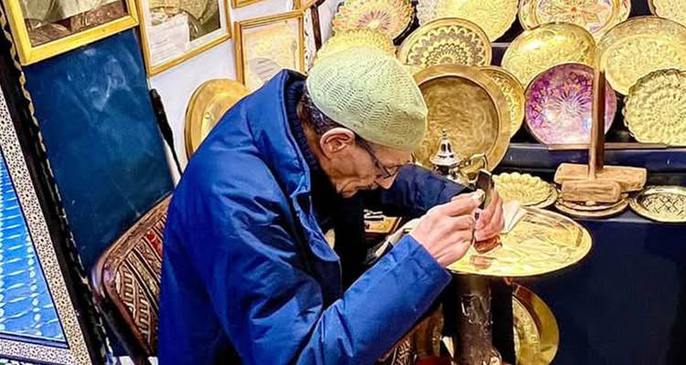 Artesano trabajando en un plato decorativo en un mercado tradicional.