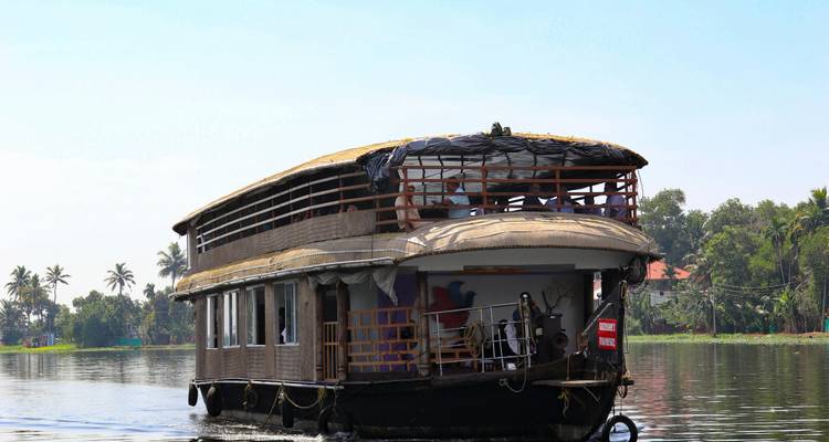 Houseboat cruising on a river with trees in the background.