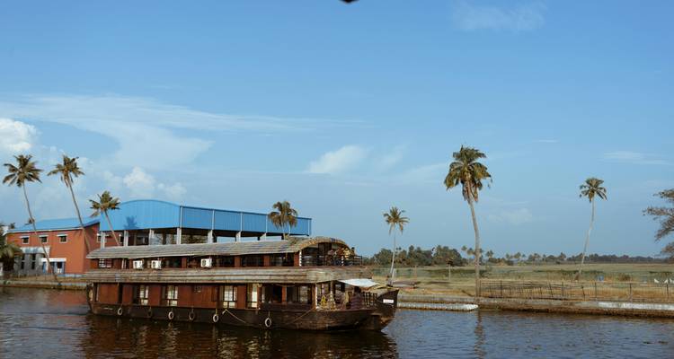 Houseboat on a canal with blue sky and palm trees.
