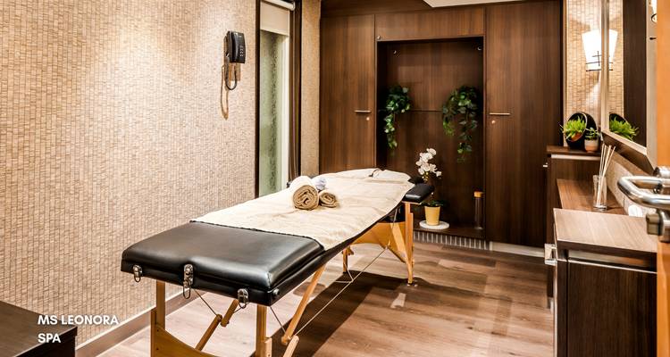 Spa-Bereich im Inneren eines Kreuzfahrtschiffs mit einer Massageliege und Dekoration.