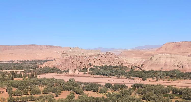 Een landschap met groene velden en bergen, voorzien van een watermerk in de hoek.