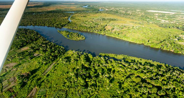 Luchtfoto van een weelderig groen landschap met een rivier en velden.