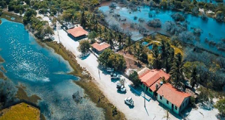 Vogelvluchtaanzicht van een tropische nederzetting omgeven door water en bomen.