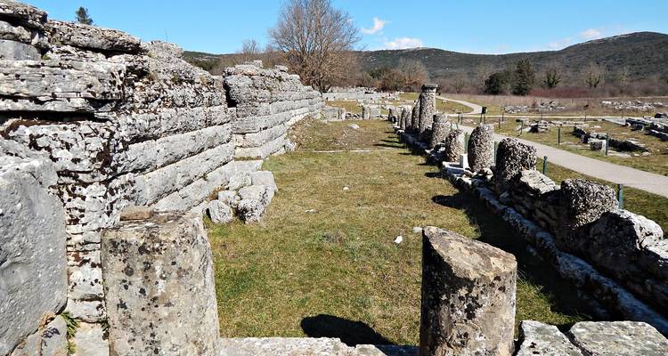 Ruinas de piedra y columnas en pie en el antiguo santuario de Dodona en un día soleado.