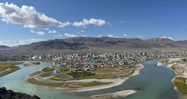 Vista panorámica de una ciudad con ríos y montañas al fondo.