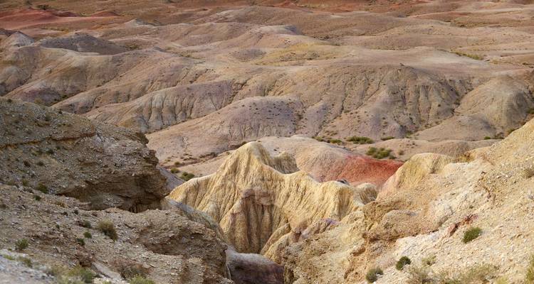 Formaciones rocosas erosionadas con patrones coloridos y grietas profundas.