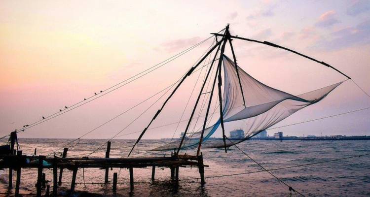 A traditional Chinese fishing net silhouetted against a colorful sky at sunset.
