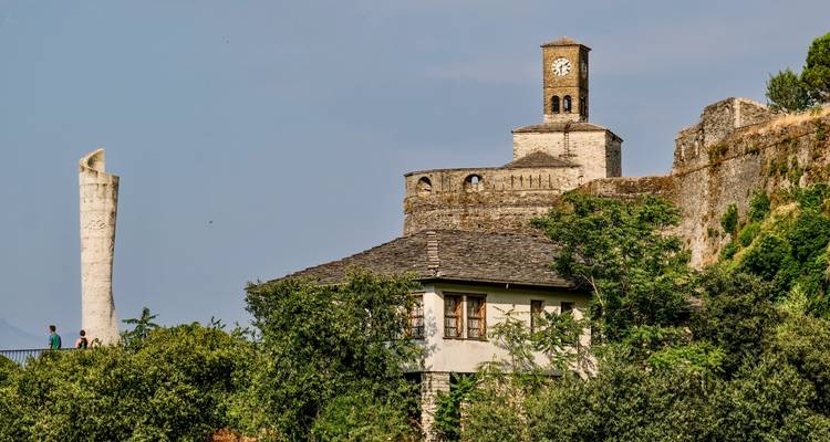 Une forteresse historique en pierre avec une tour d'horloge se dressant contre un ciel dégagé.