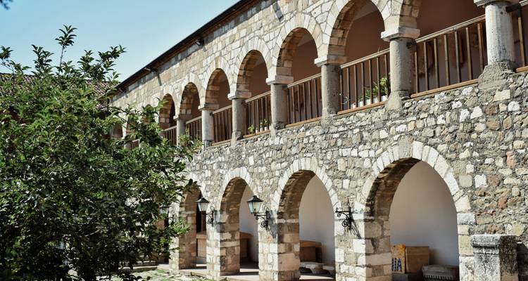 Un bâtiment historique avec des colonnades voûtées et une façade en pierre.