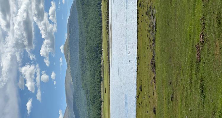 Escena pacífica de lago con montañas y árboles.