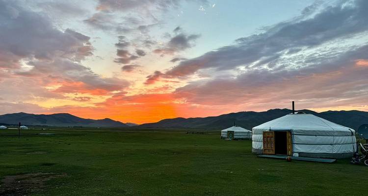 Yurtas y una puesta de sol sobre llanuras herbosas.