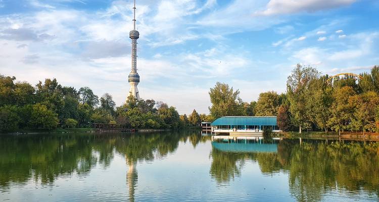 Gran torre de telecomunicaciones junto a un lago reflectante.