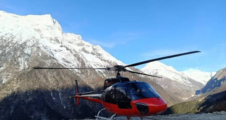 Helicopter on a mountainous plateau with snow-capped mountains in the background.