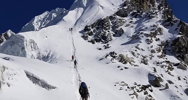 Climbers on a snowy mountain slope approaching the summit.