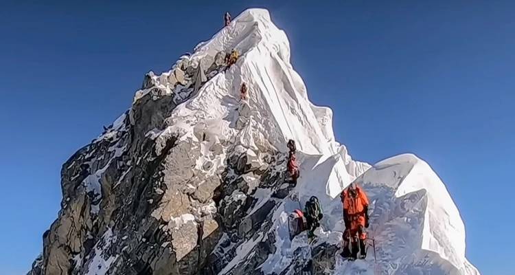 Group of climbers on a rocky, snow-covered peak.