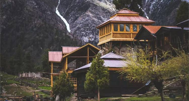 Wooden lodges in a mountainous area with trees.