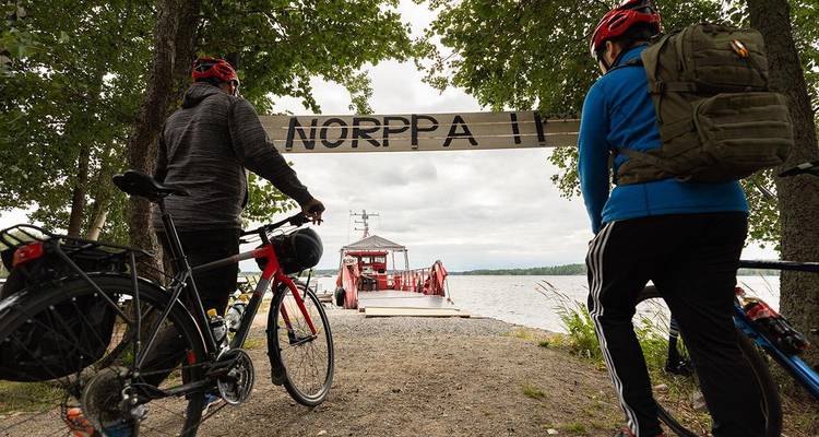 Deux cyclistes observant un ferry amarré près d'un lac.