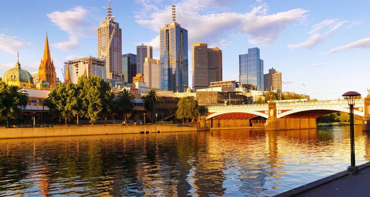 City skyline reflecting on calm river at sunset.