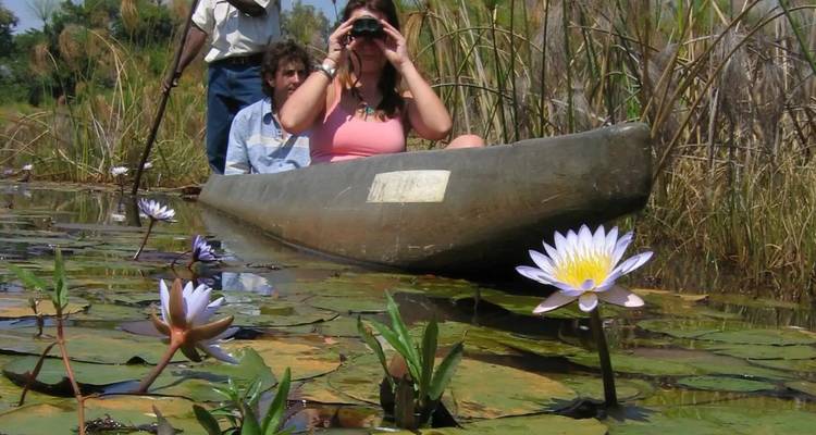 Mensen in een kano met waterlelies op de voorgrond.