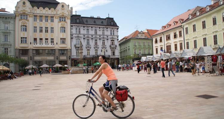 Mujer andando en bicicleta en una plaza europea con hermosos edificios antiguos