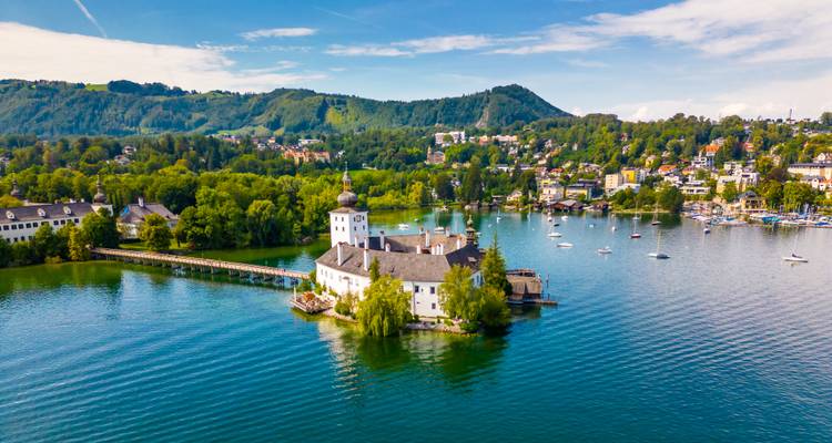 Vista aérea del pintoresco Schloss Ort en una pequeña isla en un tranquilo lago alpino.