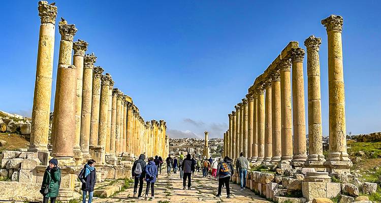 Tourists walking along the ancient Roman columns in Jerash.