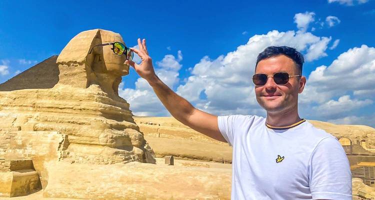 Tourist posing with the Sphinx and Great Pyramids in the background.