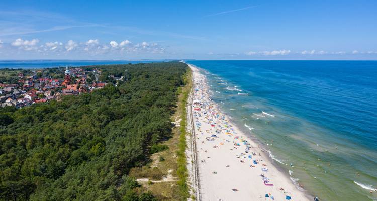 Larga playa arenosa con gente disfrutando del sol.