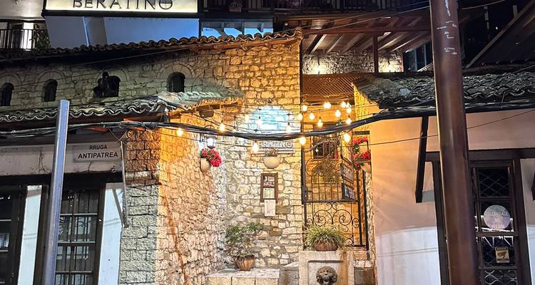 Sendero de piedra y arquitectura rústica iluminados por la noche en Berat.