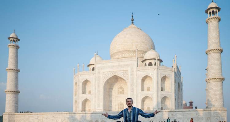 Man posing with open arms in front of the Taj Mahal.