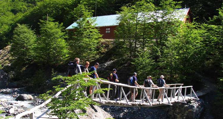 Excursionistas cruzando un puente en un entorno forestal.