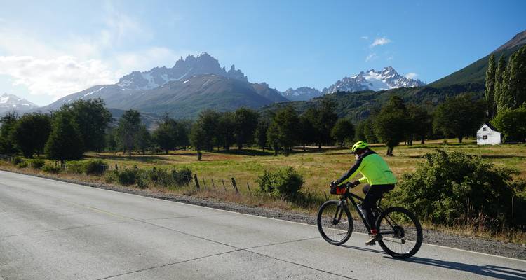 Cycliste sur une route ensoleillée avec des montagnes en arrière-plan.