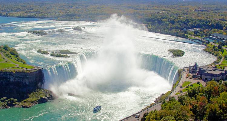 Spektakuläre Luftaufnahme der Horseshoe Falls mit aufsteigendem Nebel und einem Ausflugsboot, das sich dem Wasserfall nähert.