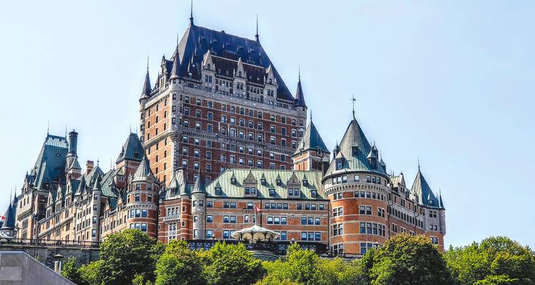Ikonisches Château Frontenac, das sich über grüne Bäume und alte Steinmauern in Quebec City erhebt.