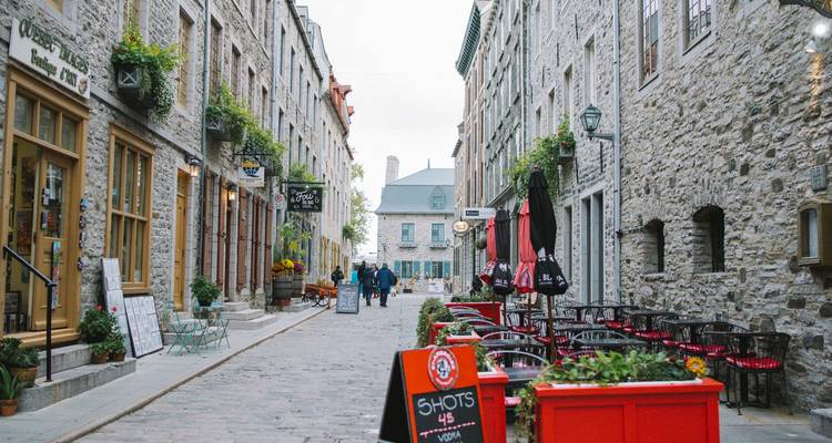 Charmante Kopfsteinpflastergasse mit Steingebäuden, Cafés und Blumenkästen in der Altstadt von Quebec.