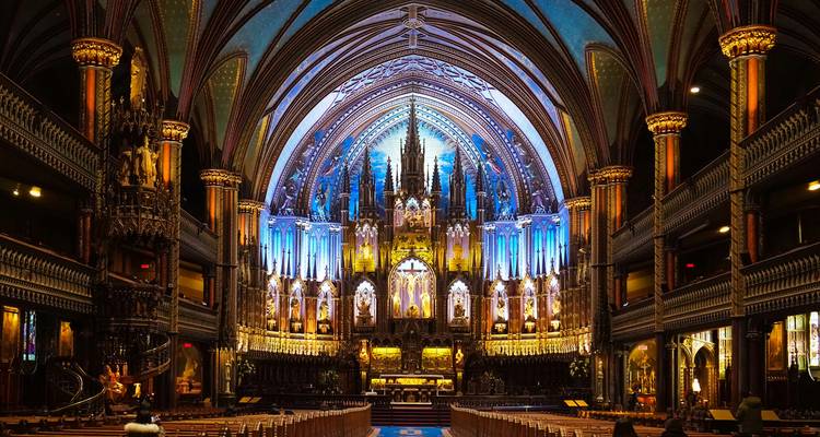 Beleuchtetes Inneres der Notre-Dame-Basilika in Montreal mit leuchtendem blauem und goldenem Altar.