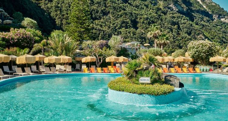 Pool area with umbrellas and green hillside in the background.