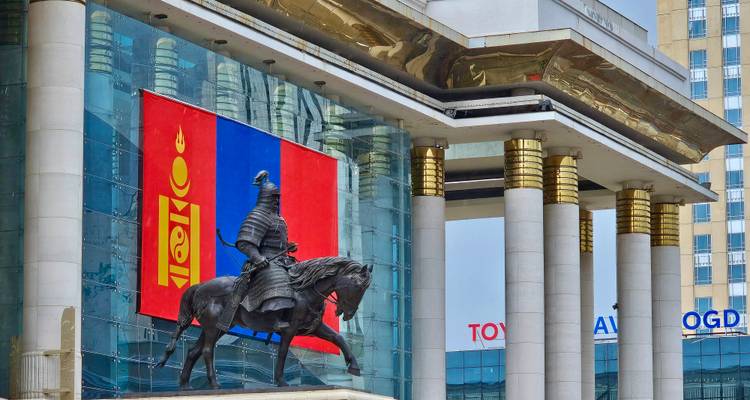 Estatua de un jinete frente a un edificio con la bandera de Mongolia en Ulán Bator.