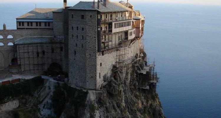 Monasterio encaramado en el borde de un acantilado con vista al mar.