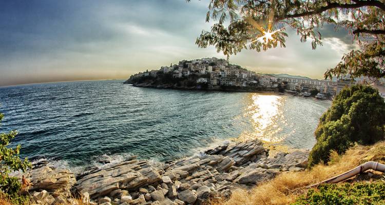 Pueblo costero en una colina con una puesta de sol sobre el agua.
