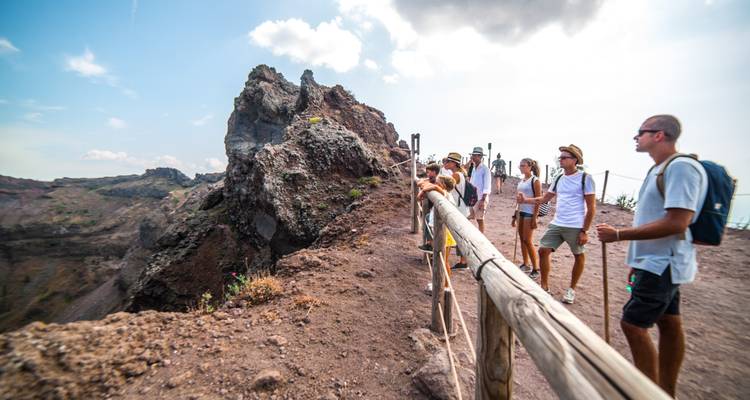 Un grupo de turistas en un acantilado con vista a un cráter volcánico.