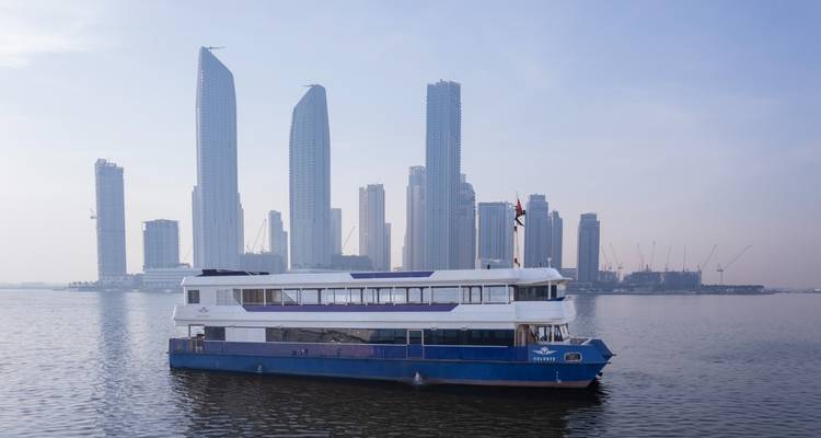 Barco navegando con altos rascacielos al fondo.