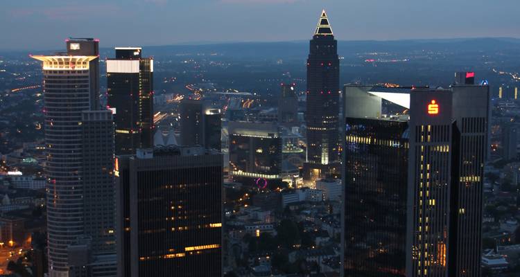 Horizonte de Frankfurt al atardecer con edificios iluminados.
