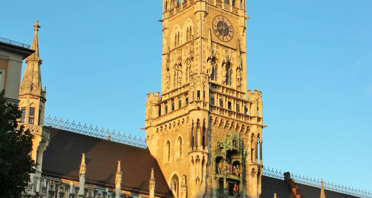 Bâtiment historique avec une tour d'horloge éclairée par la lumière du soleil.